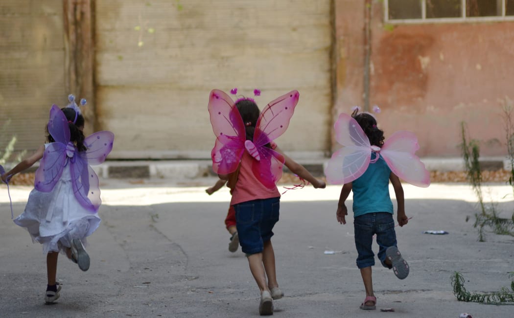 Palestinian girls wearing costumes play in the besieged (by IS) Yarmuk refugee camp in the Syrian capital Damascus on August 31, 2015.