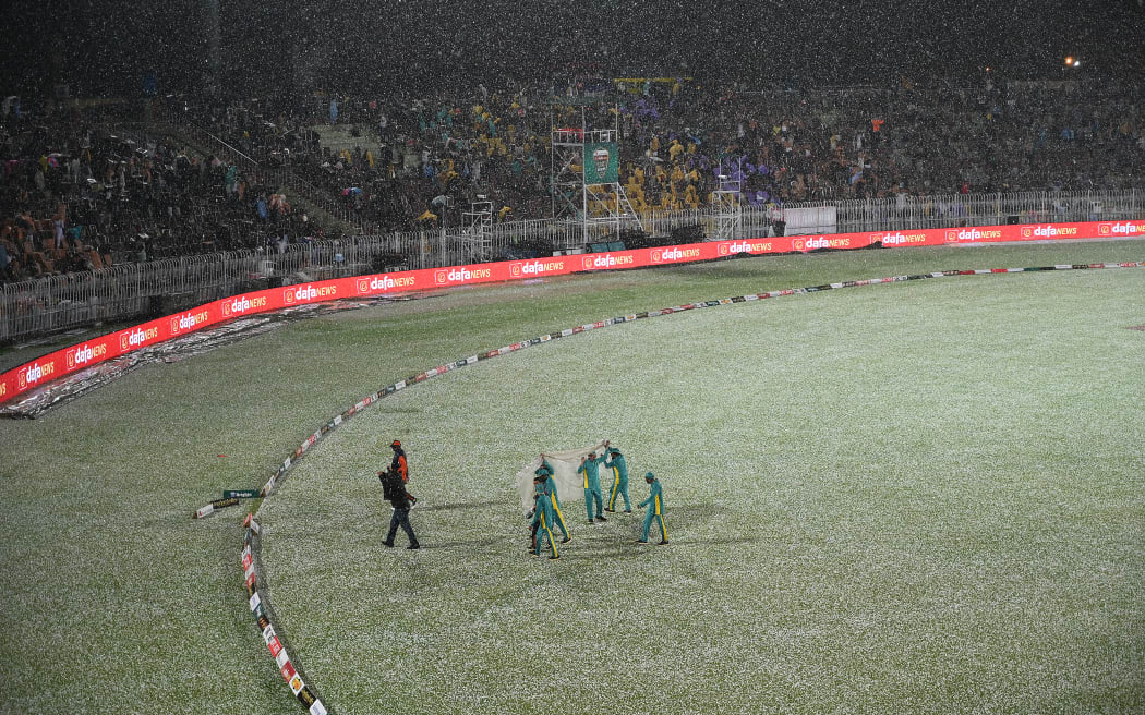 Ground staff leave after covering the pitch from a hailstorm shower that stopped the game during the fourth Twenty20 international cricket match between Pakistan and New Zealand at the Rawalpindi Cricket Stadium, 2023.