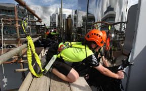 A construction worker peels away the protective layer from a stainless steel panel on the exterior of the new Len Lye Centre in New Plymouth.