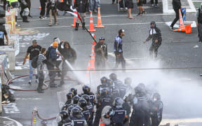 Protesters gain control of a fire hose and aim that at police as well
