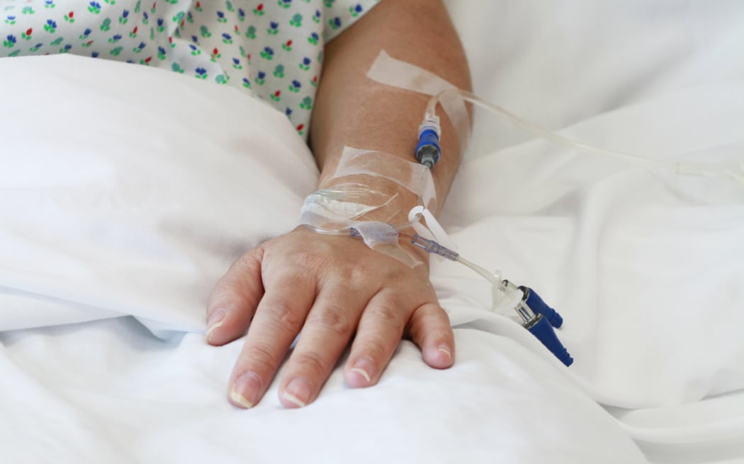 A file photo of a patient in a hospital bed with an IV drip in the arm