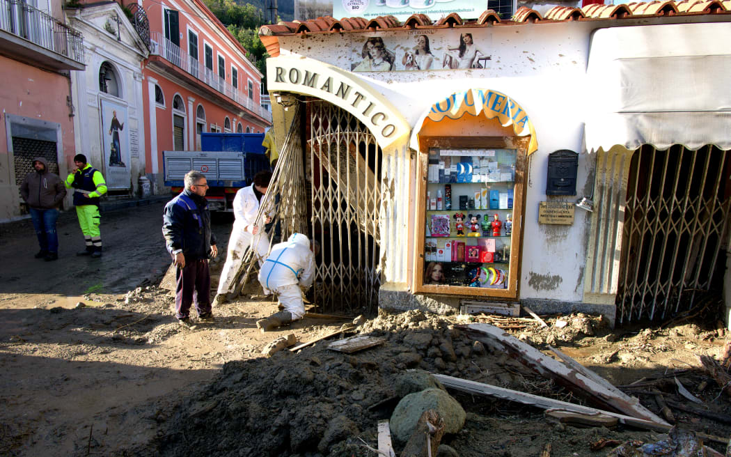People work on the damaged gate of a restaurant in Casamicciola on November 27, 2022, following heavy rains that caused a landslide on the island of Ischia, southern Italy. - Italian rescuers were searching for a dozen missing people on the southern island of Ischia after a landslide killed at least one person, as the government scheduled an emergency meeting. A wave of mud and debris swept through the small town of Casamicciola Terme early Saturday morning, engulfing at least one house and sweeping cars down to the sea, local media and emergency services said. (Photo by Eliano IMPERATO / AFP)