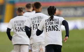 Leeds United players wear T-shirts with slogans against a proposed new European Super League during the warm up for the English Premier League football match between Leeds United and Liverpool