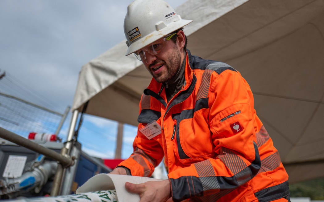 Max Vollenbroich of German firm Amex-Sanivar helps guide the folded and taped high strength liner towards the sludge pipe.