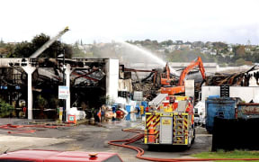 Fire crews at the scene of a recycling plant the day after a large fire engulfed the industrial building in Auckland's North Shore.