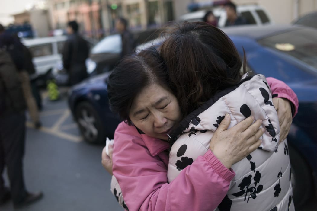 Two relatives of Chinese passengers aboard missing Malaysia Airlines flight MH370 cry as they leave the Beijing Rail Transportation Court in Beijing on March 7, 2016.