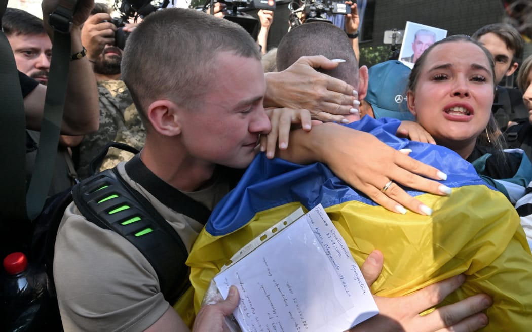 Relatives hug a released prisoner of war (POW) wrapped in a Ukrainian national flag after a prisoner swap between Ukraine and Russia on Friday.