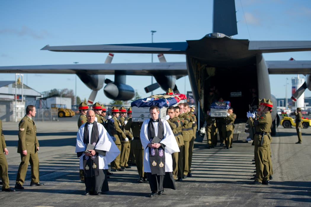 Soldiers carry the coffins from the Hercules.