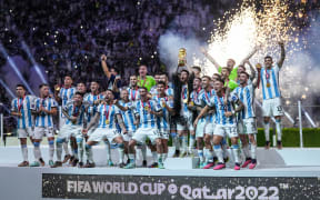 Lionel Messi of Argentina lifts trophy wearing a Bisht - traditional Arab robed as he lifts the world cup trophy surrounded by team mates uring after defeating France in a penalty shootout at the FIFA World Cup Qatar 2022 final.  (Photo by Ayman Aref/NurPhoto) (Photo by Ayman Aref / NurPhoto via AFP)