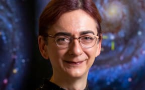 Jan Eldridge in star-patterned dress in front of image of galaxies