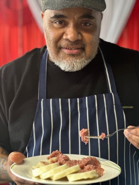 Otahūhū-based Eight Roses cafe and buffet co-owner and chef Freddy Tu'akalau holding a fork and plate with corned beef and yam.