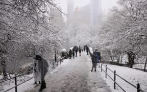 People walk through the falling snow in Central Park on February 13, 2024 in New York City. Heavy snowfall is expected over parts of the Northeast US starting late February 12, with some areas getting up to two inches (5cms) of snow an hour, the National Weather Service forecasters said. (Photo by Yuki IWAMURA / AFP)