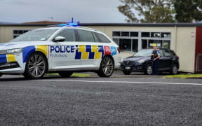 Armed police outside a school in Henderson, west Auckland, on 24 February 2024.
