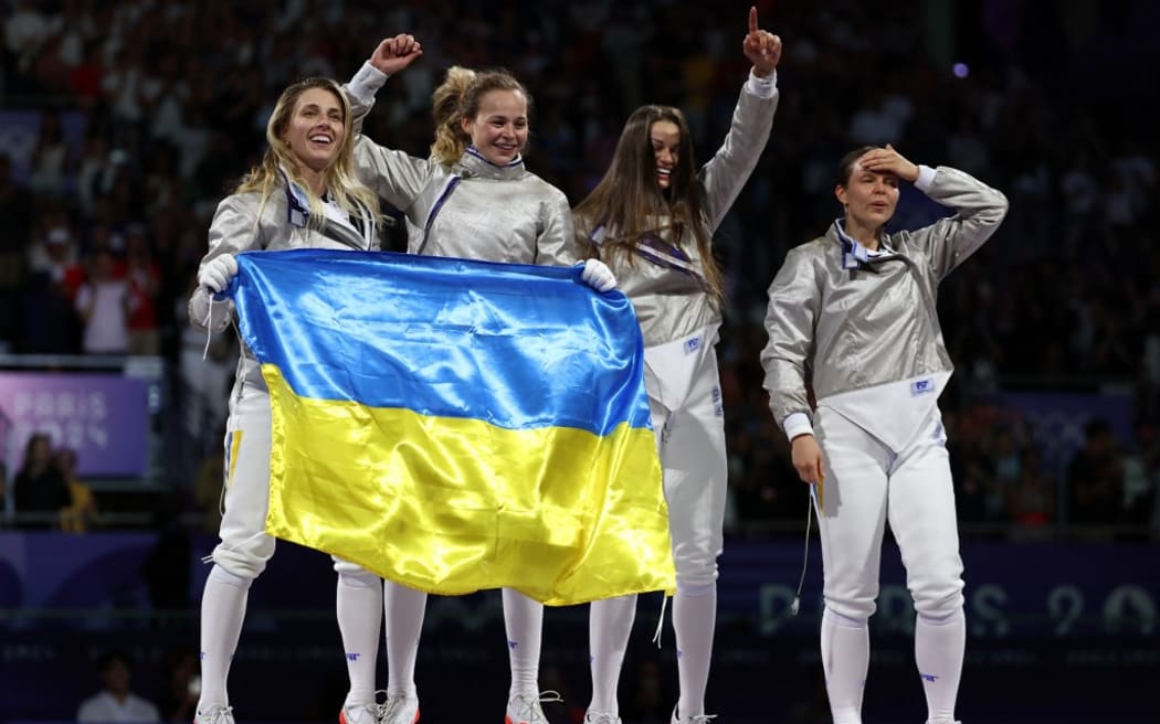 Ukraine's Olga Kharlan (L) and Ukraine's team celebrate after winning in the women's sabre team gold medal bout between South Korea and Ukraine during the Paris 2024 Olympic Games at the Grand Palais in Paris, on August 3, 2024. (Photo by Franck FIFE / AFP)