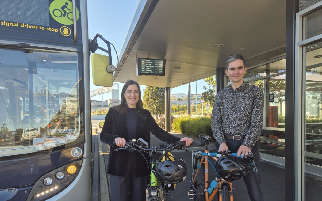 Auckland Transport Head of Public Transport Operations Pete Moth and head of Active Modes Tania Loveridge prepare to board a bus displaying a green cyclist symbol, indicating it has cycle racks onboard.