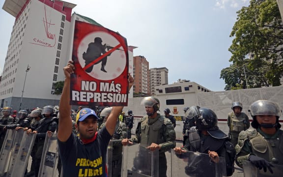 A demonstrator with a sign saying 'no more repression' standing in front of members of the national guard.