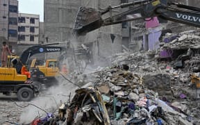Rescue workers conduct a search operation amid the debris of a collapsed residential building in Karachi on July 5, 2025. Rescue teams pulled more bodies from the rubble of a five-storey building collapse in Pakistan overnight, taking the toll on July 5 to 14 as the recovery operation continued for a second day. (Photo by Rizwan TABASSUM / AFP)