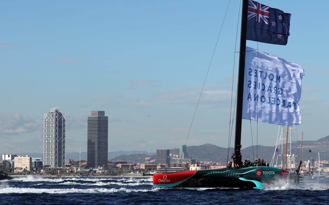 Members of the crew of defender Emirates Team New Zealand hoist a flagf reading in Catalan "Thanks a lot Barcelona" as they celebrate winning the Louis Vuitton 37th America's Cup Match, in Barcelona on October 19, 2024.