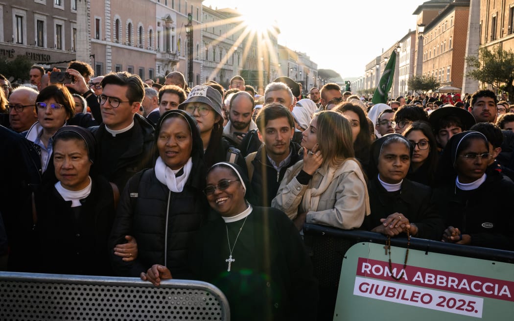 Attendees and nuns stand in the street as they wait before late Pope Francis' funeral ceremony at St Peter's Square in The Vatican on April 26, 2025. (Photo by JEFF PACHOUD / AFP)