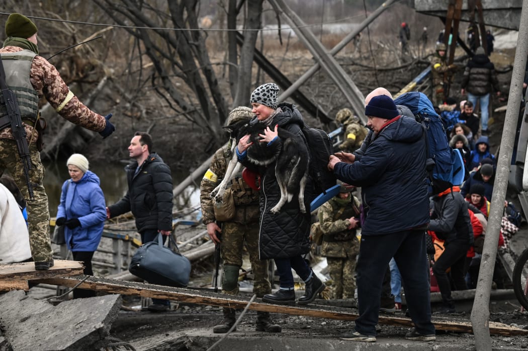 People cross a destroyed bridge as they  evacuate the city of Irpin, northwest of Kyiv, during heavy shelling and bombing on March 5, 2022, 10 days after Russia launched a military invasion of Ukraine.