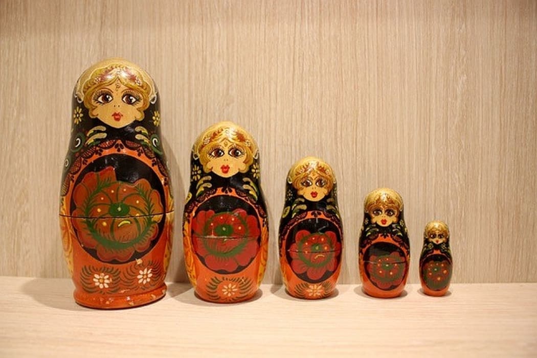 Five highly-painted wooden matryoshka Russian dolls lined up in order of height.