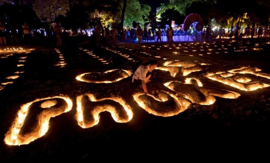 A Thai student places candles on a sand sculpture during commemorations on the the tenth anniversary of the 2004 tsunami at Patong beach in Phuket.