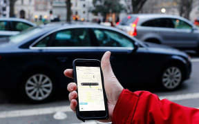 An UBER application is shown as cars drive by in Washington, DC
