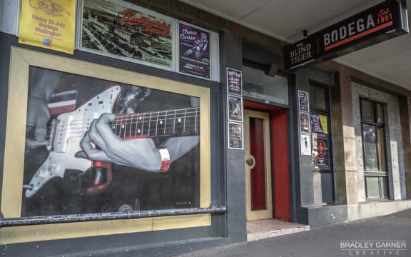 The front of Bodega in 2016. Photo by Bradley Garner. Wall mural of Andrew Wilson from Die! Die! Die! by NZ artist Mark Rutledge.