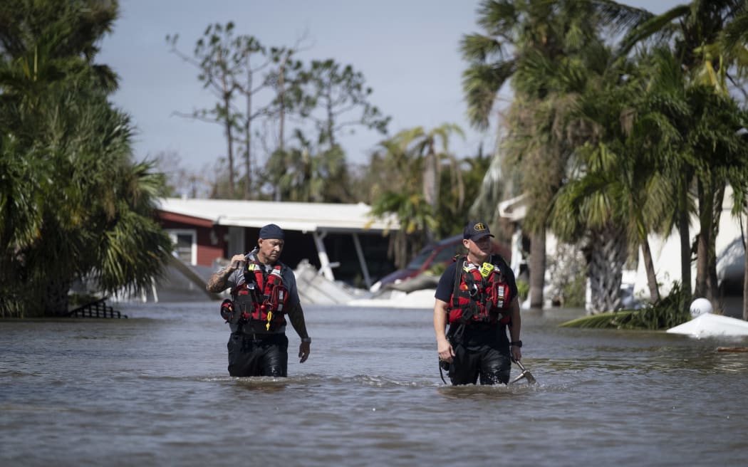 Search and rescue personnel wade through the waters of a flooded neighborhood as they search for survivors in the aftermath of Hurricane Ian, in Fort Myers, Florida.