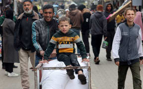 A displaced Palestinian youth pushes a cart loaded with bags of flour they received from the United Nations Relief and Works Agency for Palestine Refugees (UNRWA) in Rafah in the southern Gaza Strip on January 28, 2024, amid ongoing battles between Israel and the Palestinian militant group Hamas. Several key donor countries to the UN agency for Palestinian refugees said they would halt funding following Israeli charges that some UNRWA staff took part in Hamas's October 7 attack. (Photo by AFP)