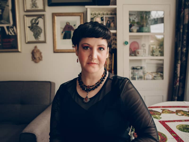 Una Cruickshank - a woman with short black hair and a black top - looks enquiringly at the camera.