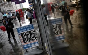Pedestrians walk past a board displaying the price of Euro and US dollars against the British pound.