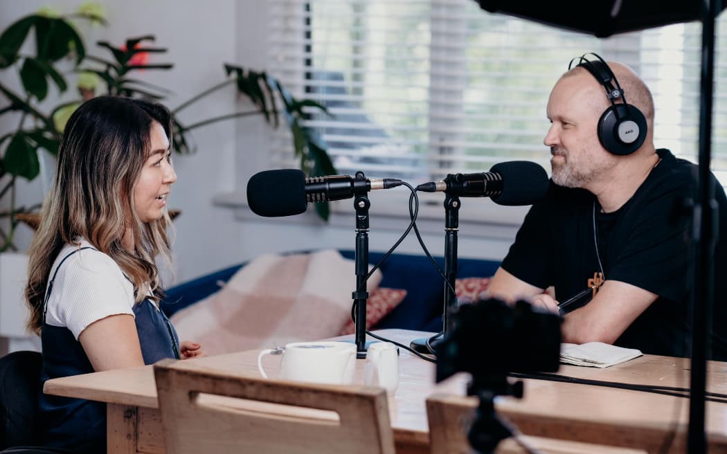 Journalist Olivia Shivas sits across a desk from Reverend Frank Ritchie.