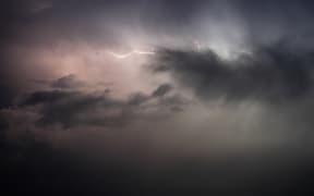 A lightning bolt illuminates the sky over northwest Syria, above the refugee camps, on September 20, 2024. The horizon flashes with the lightning's glow, briefly revealing the tents in sharp detail. (Photo by Rami Alsayed/NurPhoto) (Photo by Rami Alsayed / NurPhoto / NurPhoto via AFP)