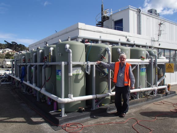 Stan Abbott stands next to the Roof Water Research Centre on the roof of Massey University in Wellington, which comprises 16 large water tanks and a sophisticated weather monitoring system.