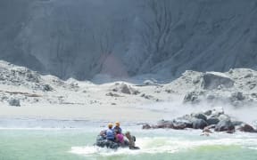 This handout photograph courtesy of Michael Schade shows White Island Tour operators rescuing people minutes after the volcano on New Zealand's White Island erupted on December 9, 2019.