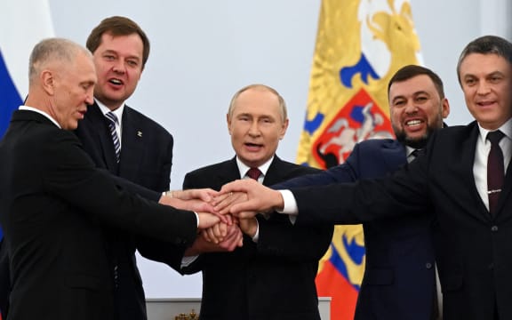 (L-R) The Moscow-appointed heads of Kherson region Vladimir Saldo and Zaporizhzhia region Yevgeny Balitsky, Russian President Vladimir Putin, Donetsk separatist leader Denis Pushilin and Lugansk separatist leader Leonid Pasechnik join hands after signing treaties formally annexing four regions of Ukraine Russian troops occupy, at the Kremlin in Moscow on September 30, 2022. (Photo by Grigory SYSOYEV / SPUTNIK / AFP)