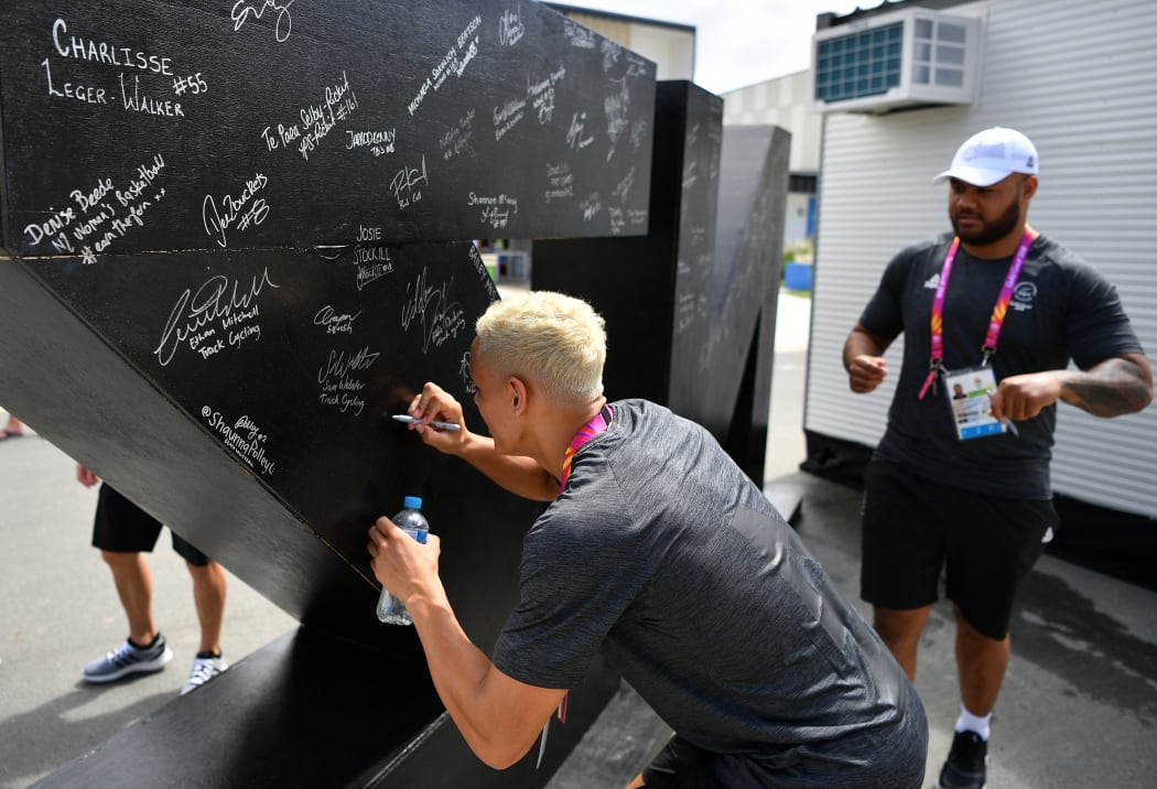 Athletes sign the NZ pou at the 2018 Commonwealth Games village