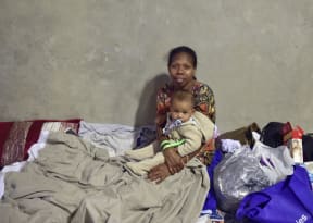 A woman and her baby take at a temporary cyclone shelter in the town of Ayr in far north Queensland.