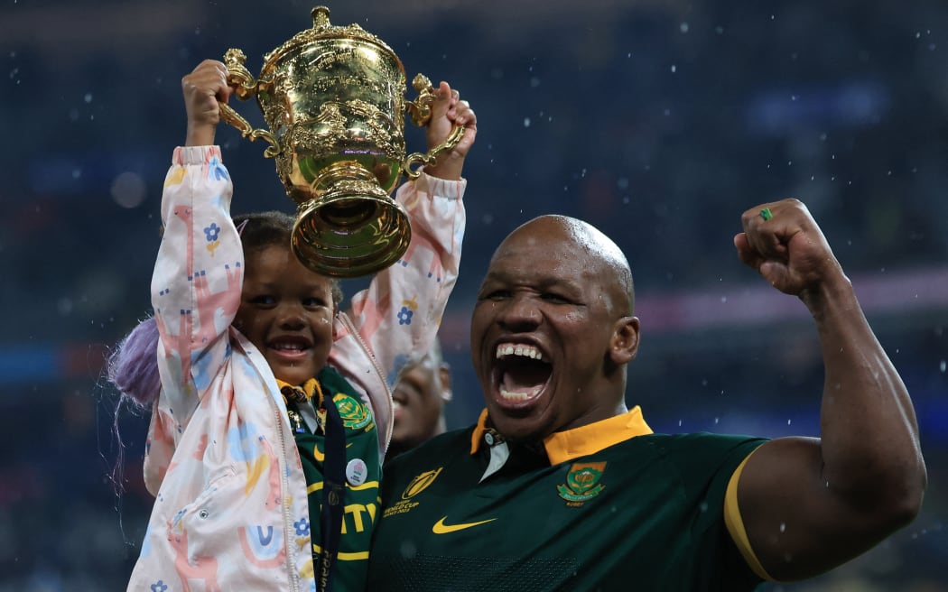 South Africa's hooker Bongi Mbonambi's daughter, Esa (L), raises the Webb Ellis Cup in the air as she is carried by her father as South Africa's players celebrate winning the France 2023 Rugby World Cup final match against New Zealand at the Stade de France on 28 October, 2023.