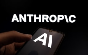 The Anthropic AI logo appears on a smartphone screen and as the background on a laptop computer screen in this photo illustration in Athens, Greece, on February 24, 2026. (Photo by Nikolas Kokovlis/NurPhoto) (Photo by Nikolas Kokovlis / NurPhoto via AFP)