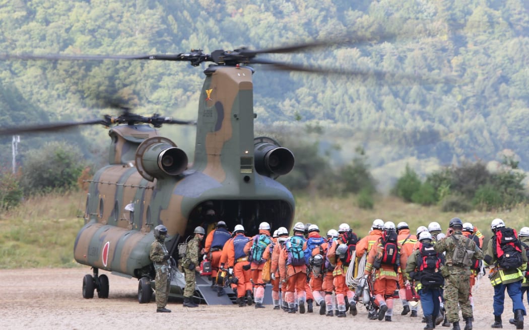 Rescue workers board a defence force helicopter today to continue the search for survivors.