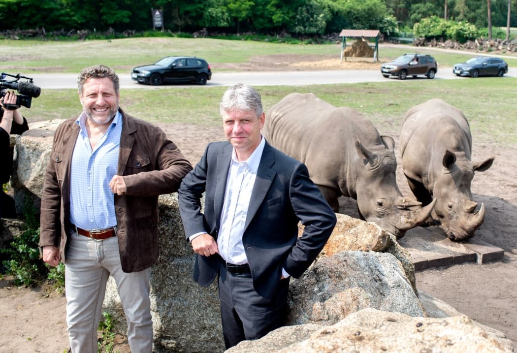 Fabrizio Sepe, Managing Director Serengeti-Park, and Thomas Hildebrandt, Professor at the Leibniz Institute for Zoo and Wildlife Research, are standing in front of a pasture in Serengeti-Park where the southern white rhinos of the zoo live.