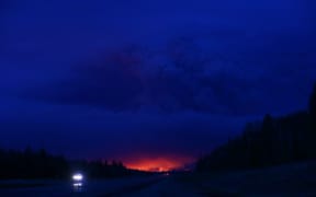 A plume of smoke hangs in the air as forest fires rage on in the distance in Fort McMurray.