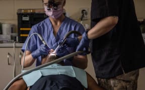 Dentist Lieutenant Amanda Rowe (left), assisted by a NZDF Dental Assistant, treats a patient in Samoa