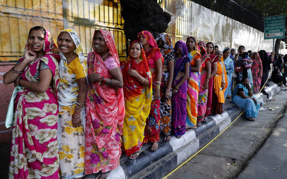 Indian women stand in a queue to deposit and exchange discontinued rupees outside a bank in Jaipur, India.