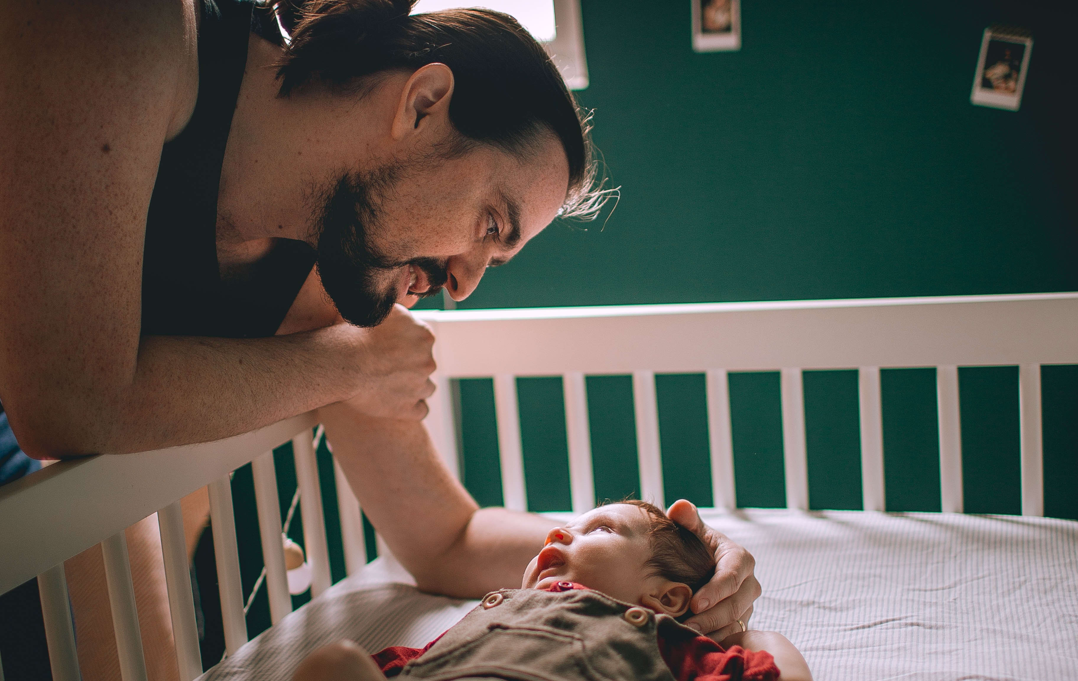 father and baby in cot
