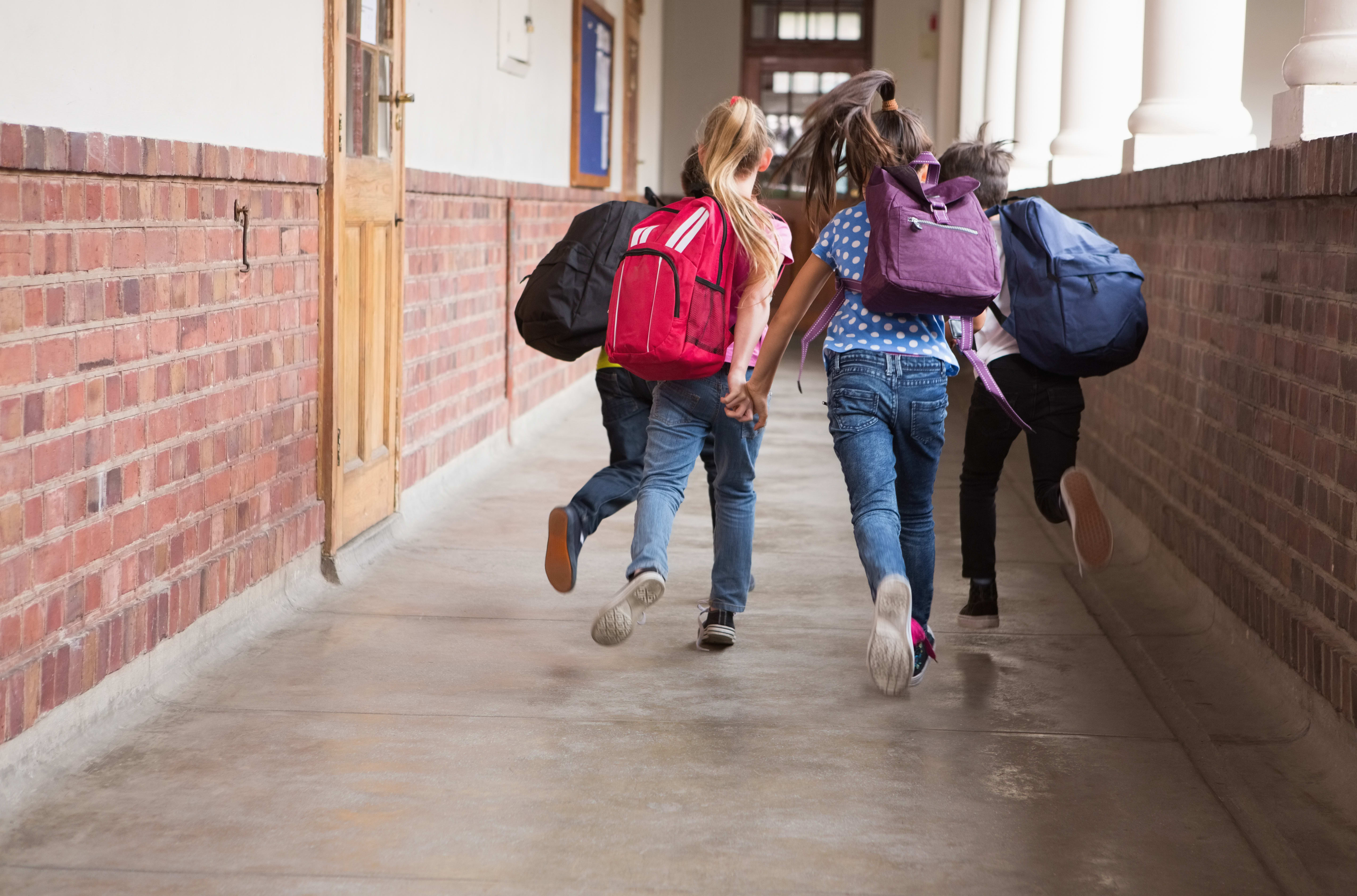 Young students running through hallway of school.