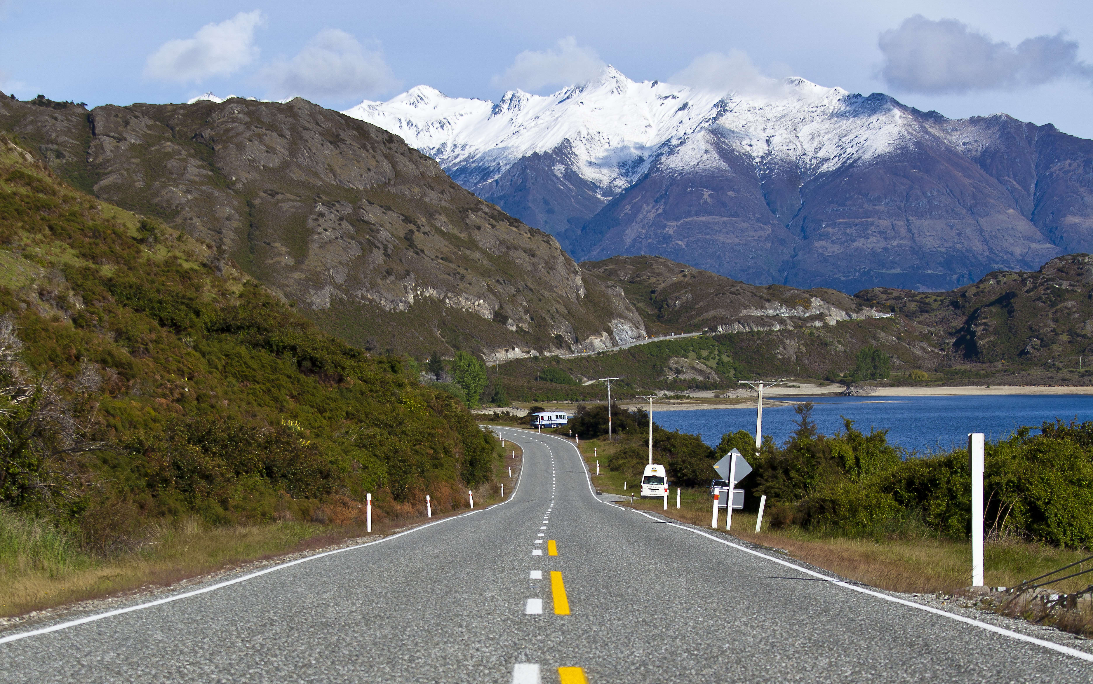 An empty stretch of road in New Zealand's South Island, with mountains and a lake in the background