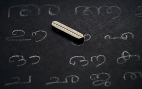 Selective focus of random Malayalam alphabets written on a kid's slate board isolated on white background.